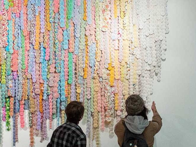 Two men are looking at a colorful art project on the wall