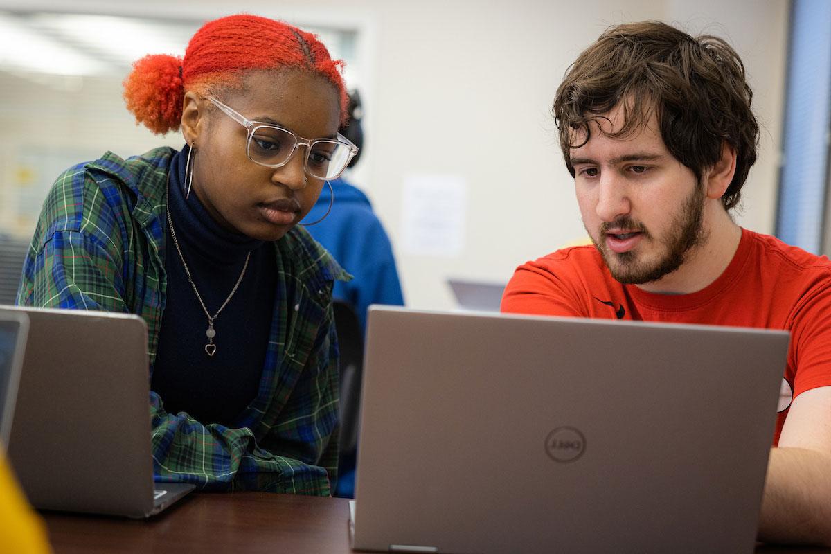 两个学生都盯着笔记本电脑聊天