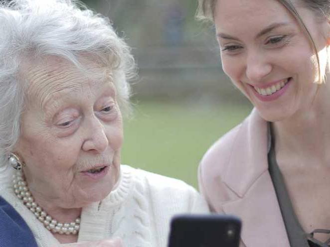 一名妇女正在用电话技术帮助老妇人