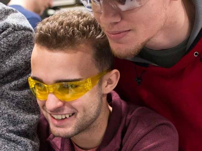 Two men with safety goggles looking down and focusing