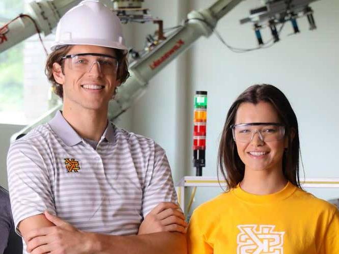 Man and woman with safety glasses and a construction hat smiling for a picture