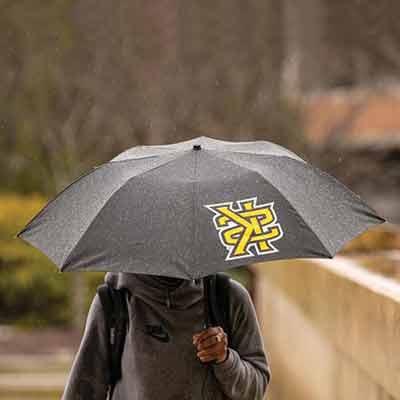 ksu student walking in rain with umbrella